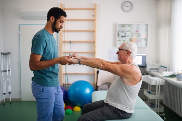 Healthcare professional assisting senior during rehabilitation therapy