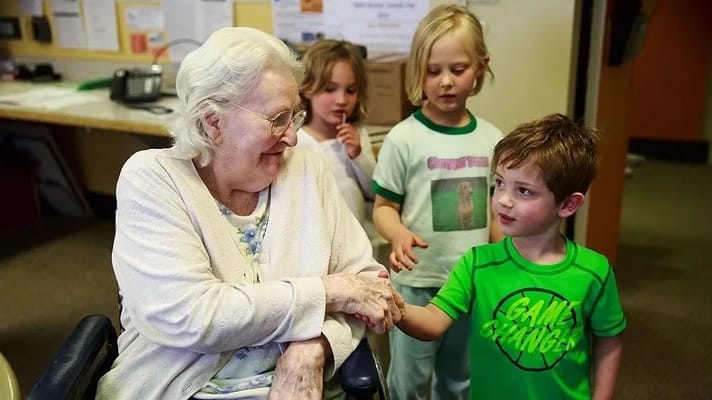 An elderly woman with young children in an activity room
