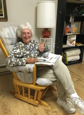 An elderly woman reading a book in a cozy chair