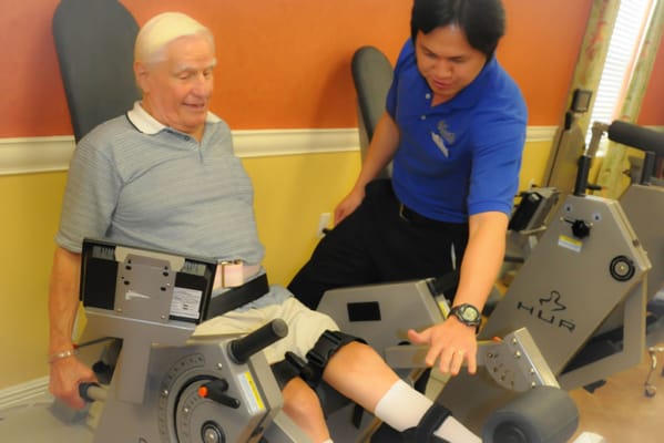 Resident exercising with staff assistance in a fitness area