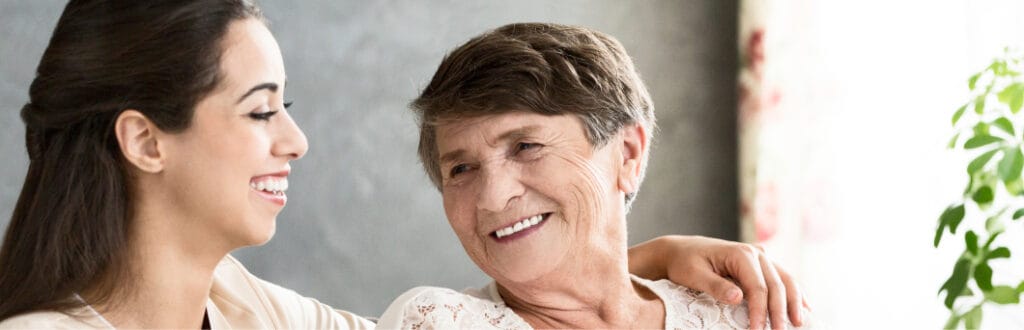 A caregiver smiling with an elderly resident indoors