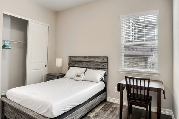 Interior view of a clean, simple bedroom with a bed and desk