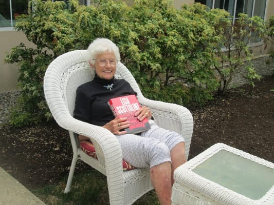 Elderly woman reading outside in a garden chair