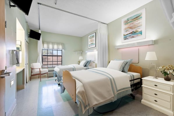 Bright resident room with two beds and artwork