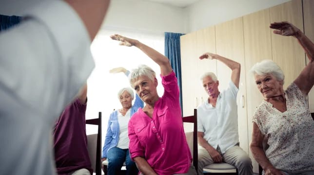 Seniors participating in a seated exercise class indoors