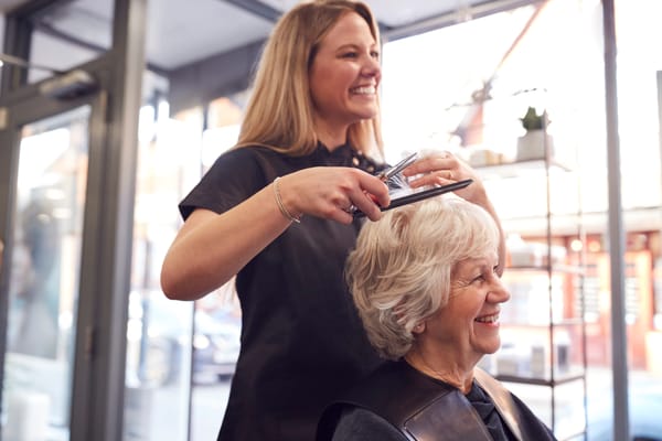 A hairstylist cutting an elderly woman's hair in a salon