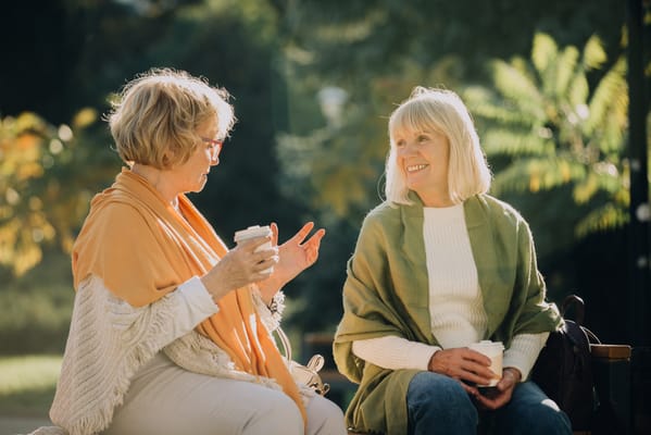 Two women engaged in conversation outdoors in a garden setting