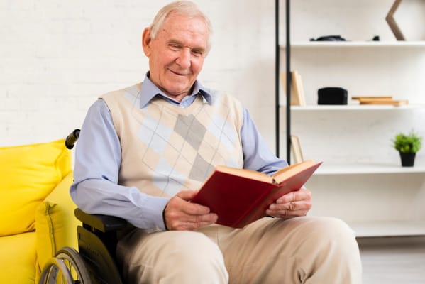 Senior man in a wheelchair reading a book in a cozy room