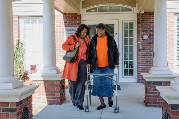 Two women walking together outside the hospice center