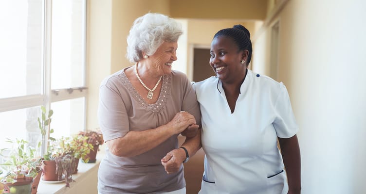 A caregiver assisting a resident down a hallway