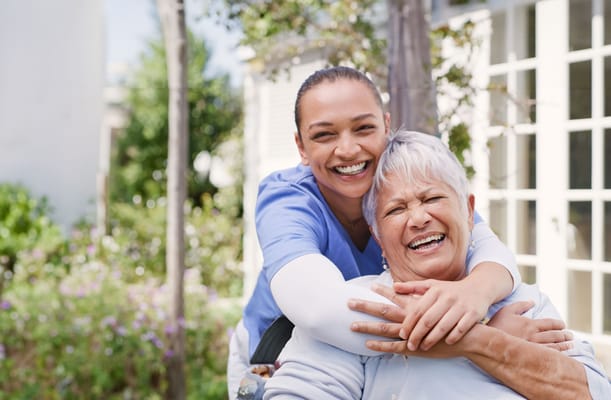 Caregiver embracing a smiling resident outdoors