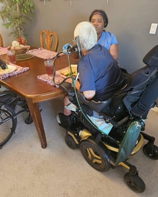 Resident enjoying a meal with staff in a dining room