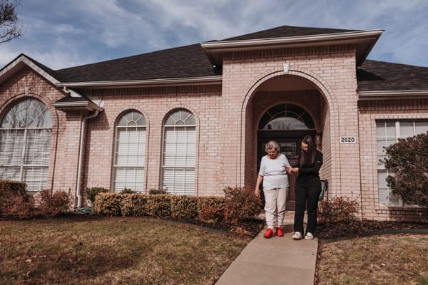 A senior resident walking with a staff member at the entrance of Brythaven Senior Living.
