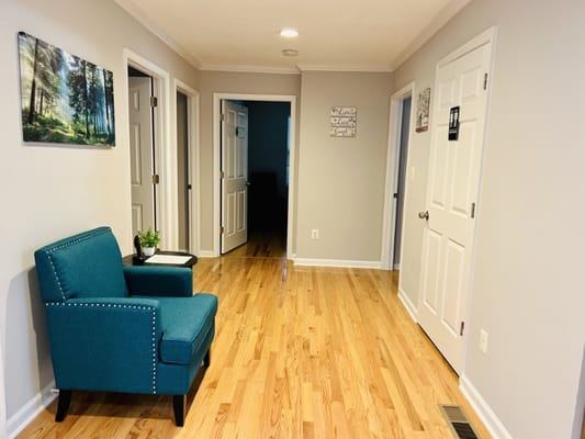 Hallway with a green chair and artwork on the walls.