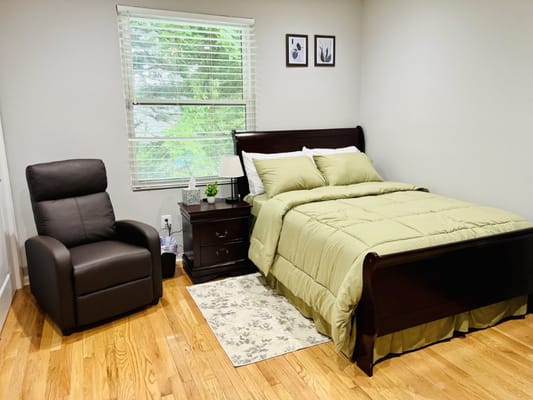 Cozy bedroom with a bed, recliner, and nightstand.
