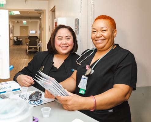 Two staff members smiling in a healthcare setting
