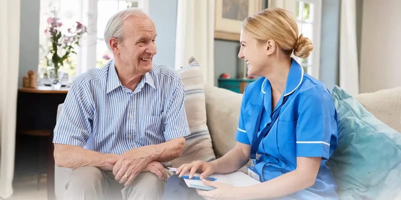 A caregiver and senior man smiling during a conversation