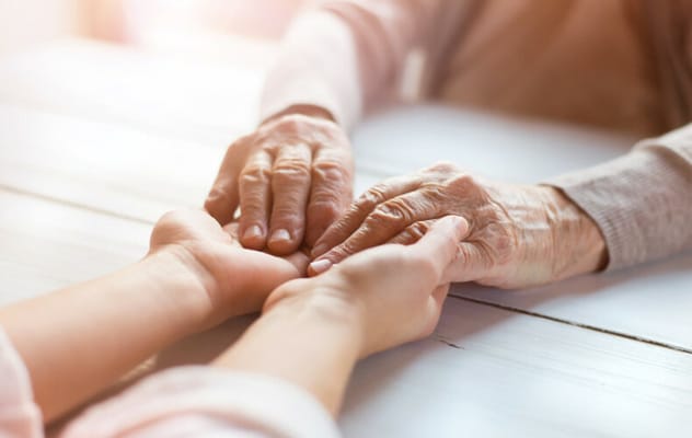 A close-up of hands of a caregiver and a senior
