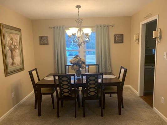 Cozy dining room with a wooden table and floral centerpiece.