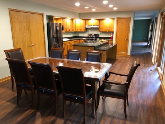 Dining room with a large wooden table and kitchen in view