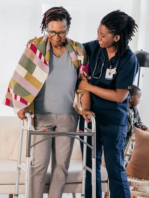 Staff assisting a resident with a walker in an indoor setting