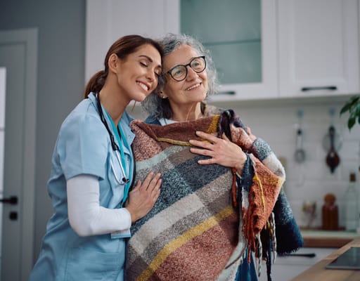 A staff member embracing a resident with a blanket