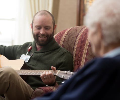 Staff member playing guitar with a resident.