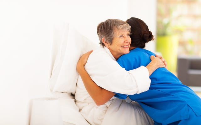Caregiver hugging a senior resident in a warm setting