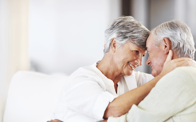Two seniors smiling and embracing each other indoors