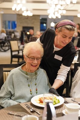 Staff serving dinner to a resident in a dining room