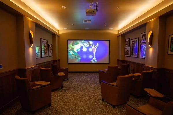A cozy movie theater room with seating and a big screen