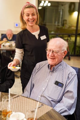 Staff member serving dessert to a resident in the dining room