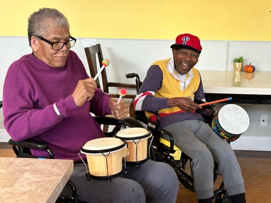 Two residents playing drums in an activity room