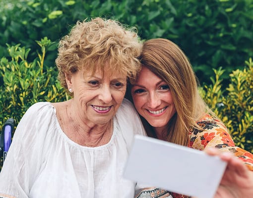A woman and a resident smiling together outdoors