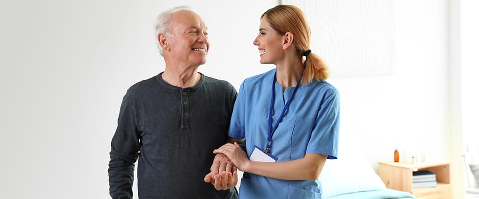 Caregiver assisting a smiling resident in a bright room