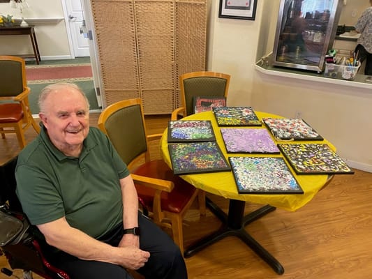 Resident showcasing artwork in a vibrant activity room
