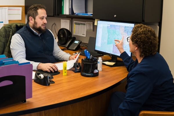 Two staff members discussing on a computer in the office