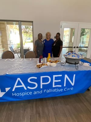 Three staff members posing at a table with refreshments.