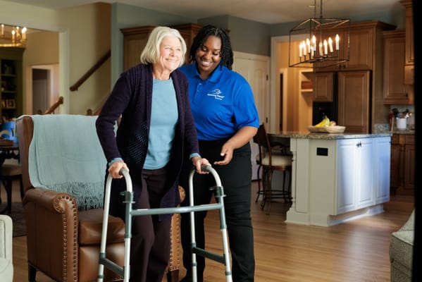 Caregiver assisting a resident with a walker in a cozy living area