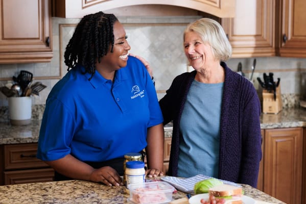 Caregiver and resident smiling in a kitchen
