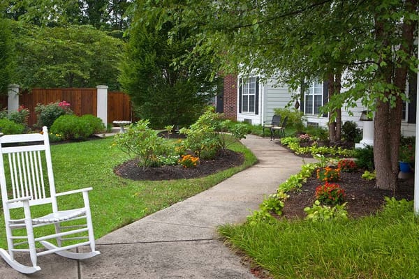 A serene garden path with flowers and a rocking chair.