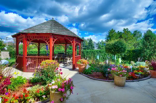 Red gazebo surrounded by colorful flowers in a garden