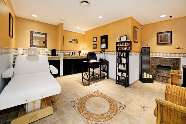 A serene spa room with a treatment chair, desk, and wellness products.