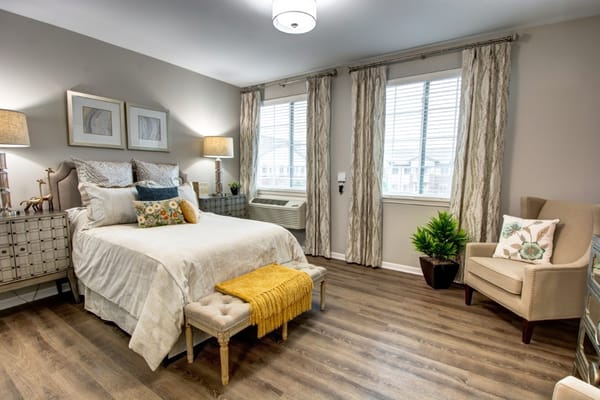 A well-decorated bedroom with a bed, side tables, and windows.