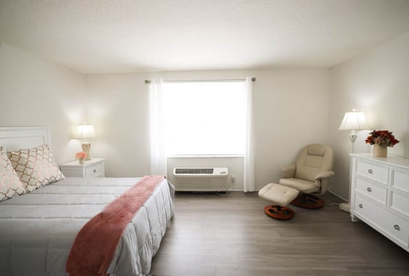 Brightly lit resident room with a bed and chair