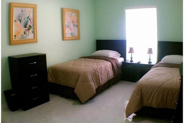 A shared bedroom with two beds, nightstands, and framed artwork.