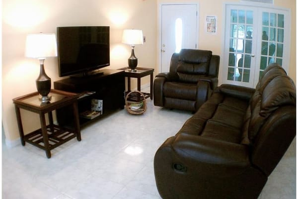 Spacious living room with a television and seating at Carmen's Goodcare Assisted Living Facility.