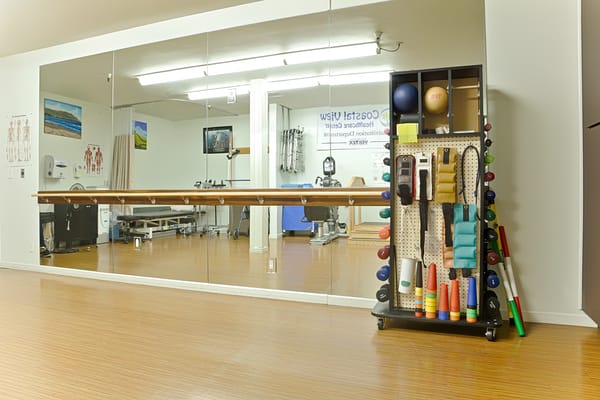 Physical therapy room with equipment and mirrors