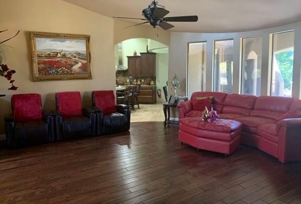 Cozy living room with red seating and dining area in the background.