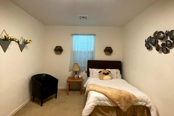 A cozy bedroom with a bed, lamp, and decorative elements.